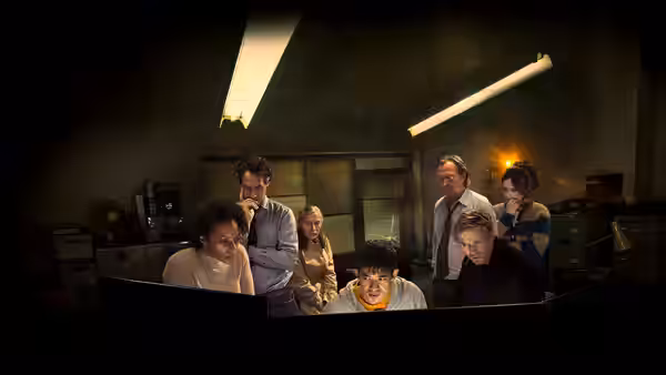The team gathered around a desk in a cluttered office