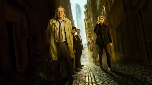Jackson Lamb (Gary Oldman) walking a cobblestone street with his team