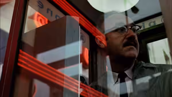 Harry Caul (Gene Hackman) standing behind glass with red neon reflections