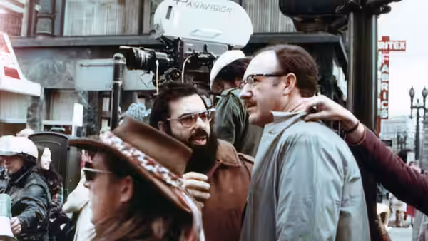 Harry Caul (Gene Hackman) speaking with crew on a city street film set