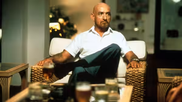 Don Logan (Ben Kingsley) seated in a chair holding a glass of beer