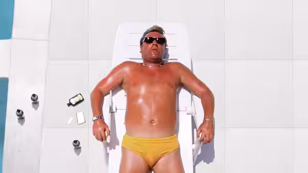 Gal (Ray Winstone) reclining on a sun lounger by a white wall