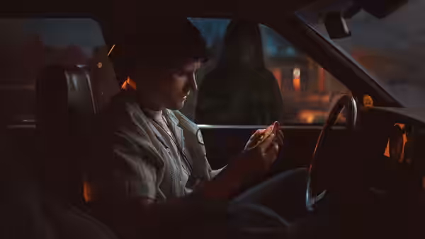 Bear (Michael Johnston) checks his phone in a car at night