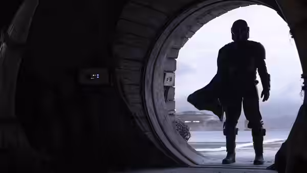 The Mandalorian (Pedro Pascal) stands silhouetted in a circular doorway overlooking mist