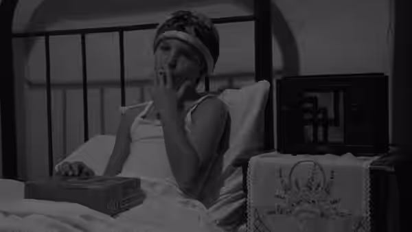 Addie Loggins (Tatum O'Neal) reclines in bed, smoking beside a box and a small radio