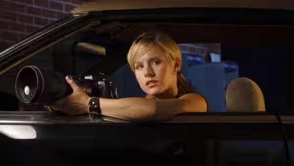 Veronica Mars (Kristen Bell) leaning from a car with a large camera