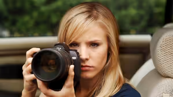Veronica Mars (Kristen Bell) aiming a camera from inside a car