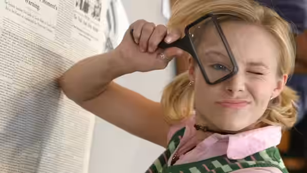 Veronica Mars (Kristen Bell) peering through a magnifying glass