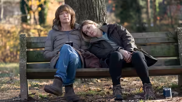 Mare Sheehan (Kate Winslet) and Lori Ross (Julianne Nicholson) sit together on a park bench