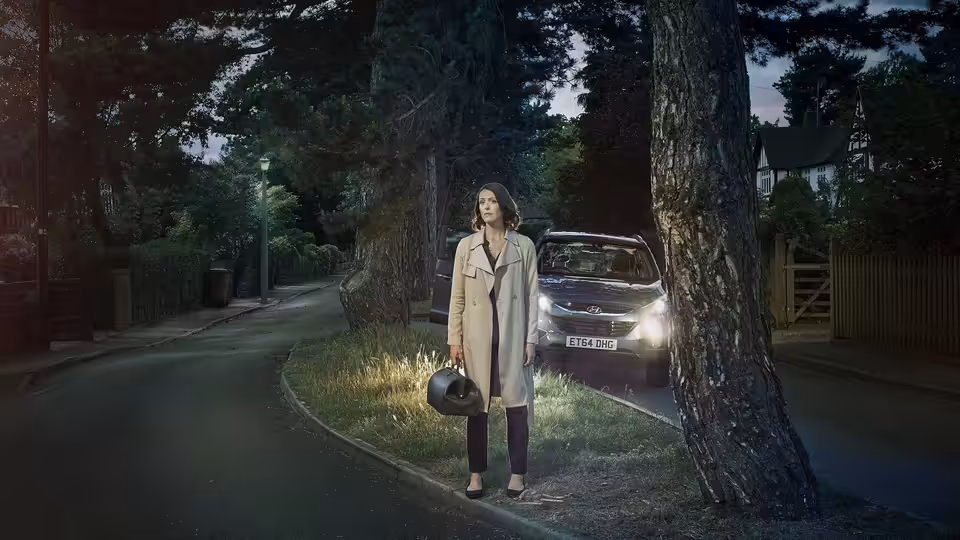 Dr Gemma Foster (Suranne Jones) stands on a suburban street holding a helmet