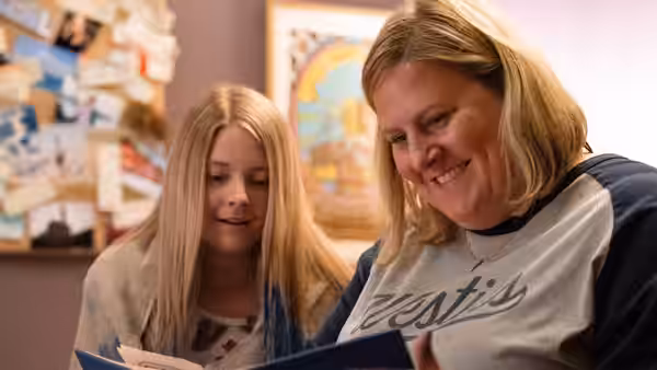 Sam Miller (Bridget Everett) reading a book with a young woman