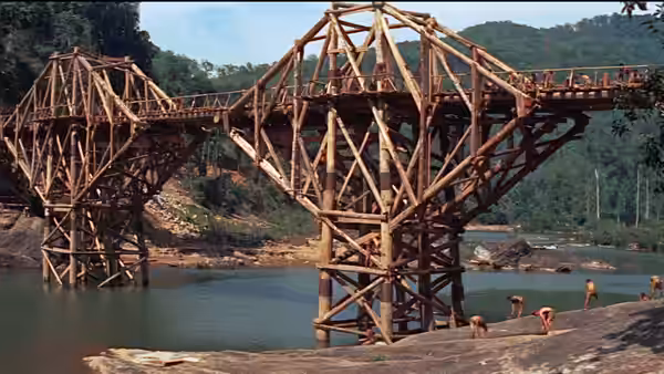 Wooden bridge over a river with men on the bank