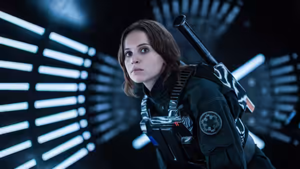 Jyn Erso (Felicity Jones) in an Imperial corridor wearing a dark uniform
