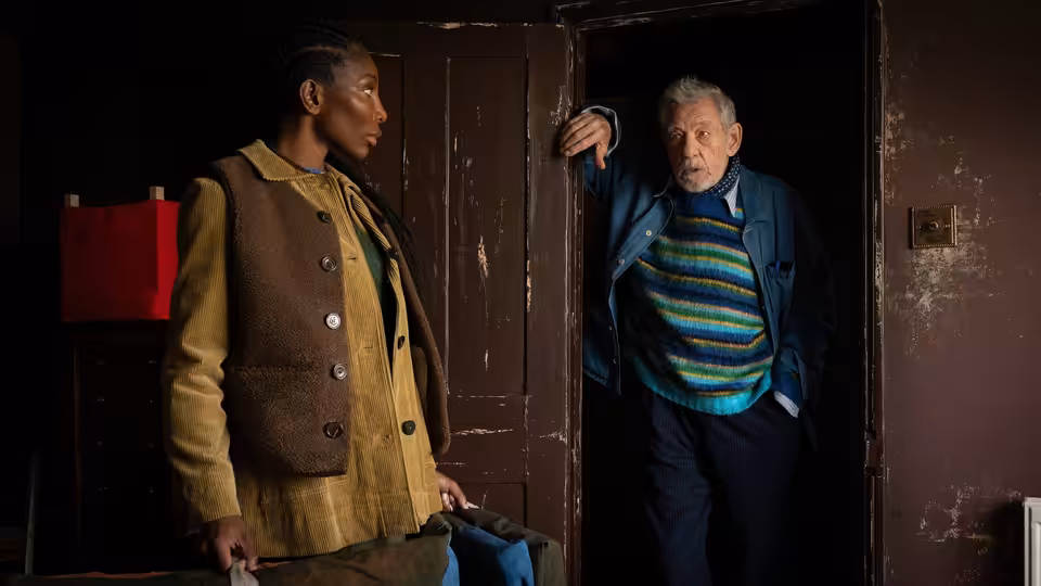 Lori Butler (Michaela Coel) stands beside Julian Sklar (Ian McKellen) at an open door