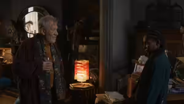 Julian Sklar (Ian McKellen) holds a glass while speaking with Lori Butler (Michaela Coel)