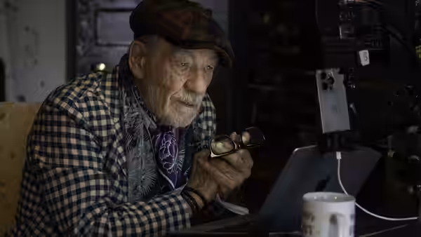 Julian Sklar (Ian McKellen) examines a pair of glasses beside an open laptop