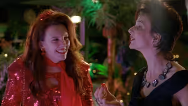 Woman in red sequins laughing with another woman outdoors at night