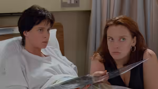 Woman in hospital bed looking at an X-ray with red-haired woman