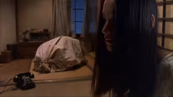 Asami Yamazaki (Eihi Shiina) sits beside a bundled figure on a tatami floor
