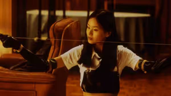 Asami Yamazaki (Eihi Shiina) stretches a wire between her hands in a furnished room