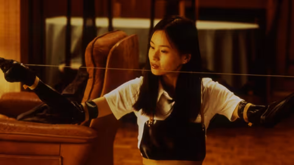 Asami Yamazaki (Eihi Shiina) stretches a wire between her hands in a furnished room