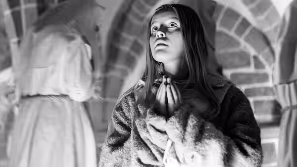 Marketa Lazarová (Magdaléna Vášáryová) clasps her hands in prayer inside a stone church
