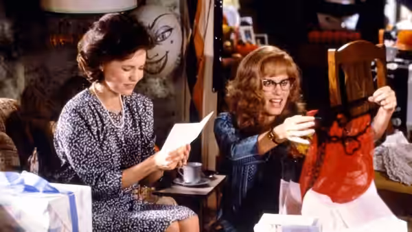 Annelle Dupuy (Daryl Hannah) reads a letter as Truvy Jones (Dolly Parton) displays a red garment