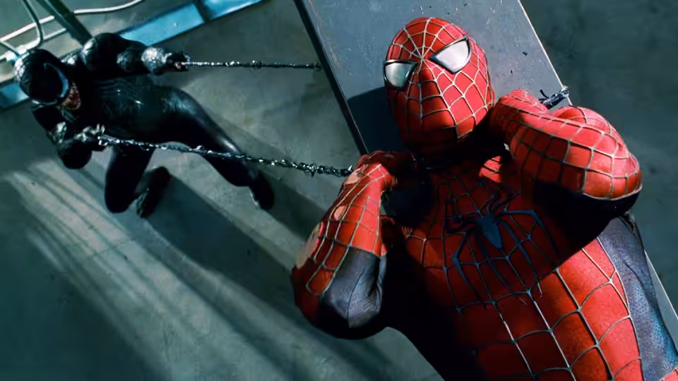 Spider-Man braces against a chain as a black-clad figure swings across a rooftop