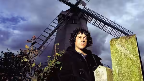Jonathan Creek (Alan Davies) standing in front of a windmill
