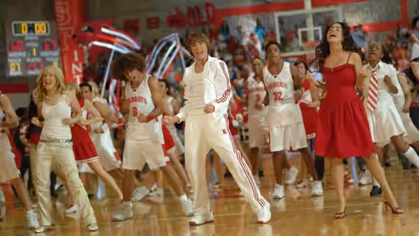 Chad (Corbin Bleu) and Taylor (Monique Coleman) dancing with students in gymnasium
