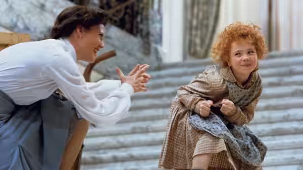 Grace Farrell (Ann Reinking) reaches toward Annie (Aileen Quinn) on wide stone steps