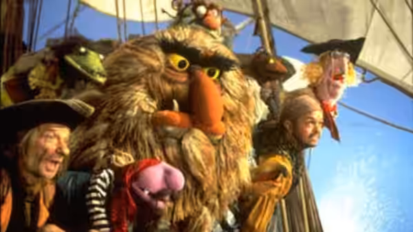 Muppet pirates in costume cheering on the deck of a sailing ship