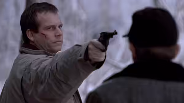 Hank Mitchell (Bill Paxton) aiming a revolver at another man in the snow