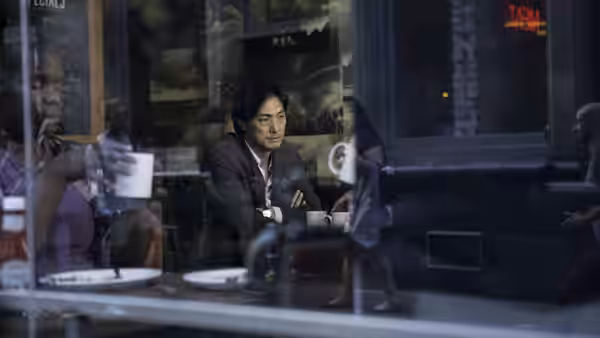 Man in a suit sits at a table inside a cafe at night