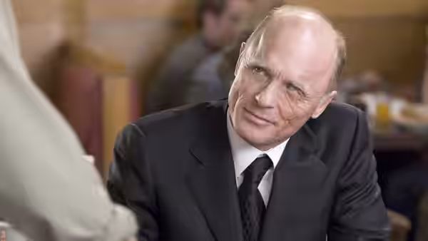 Ed Harris as Carl Fogarty seated at a table in a diner