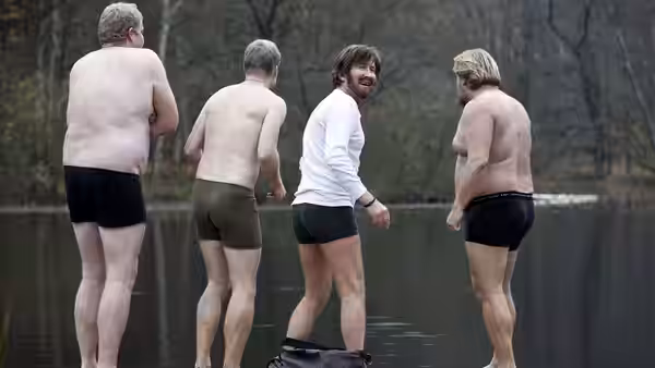 Lucas (Mads Mikkelsen) stands with three shirtless men by a lake