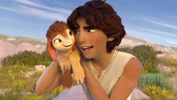 Young man smiles while holding small furry animal in sunny grassy field