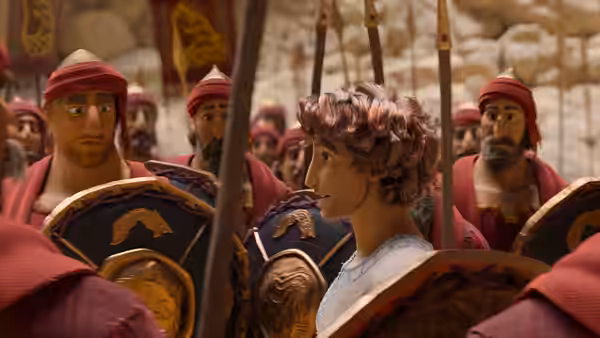 Young man in blue tunic stands among red-armored soldiers in stone hall