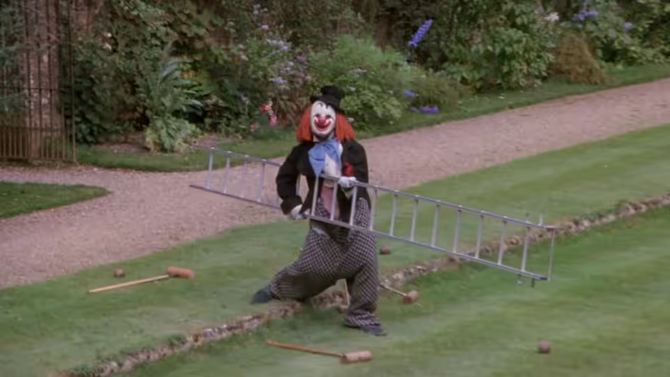 Milo Tindle (Michael Caine) as clown carrying a ladder on the lawn