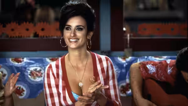 Raimunda (Penélope Cruz) smiles and claps her hands while seated indoors