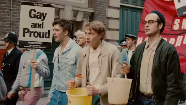 Young men march carrying a Gay and Proud sign past police