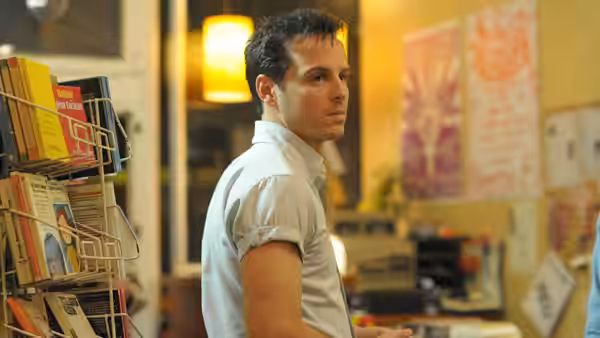 A man stands in a bookshop looking over his shoulder
