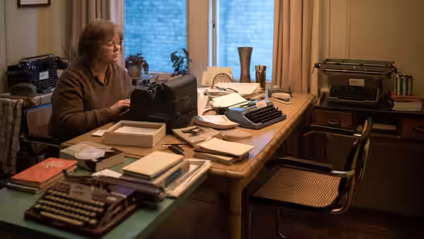 Lee Israel (Melissa McCarthy) working at a desk filled with typewriters