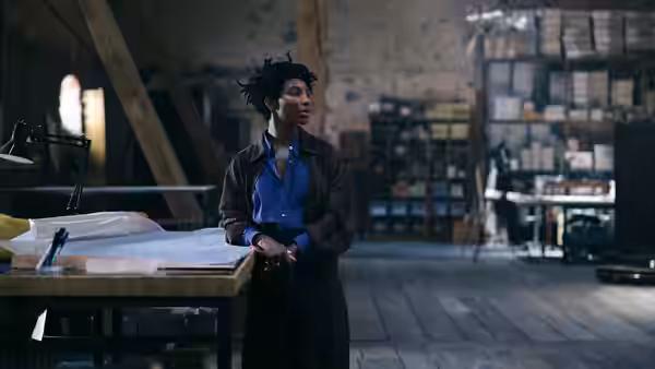 Sam Anselm (Michaela Coel) stands at a workbench in a dim studio