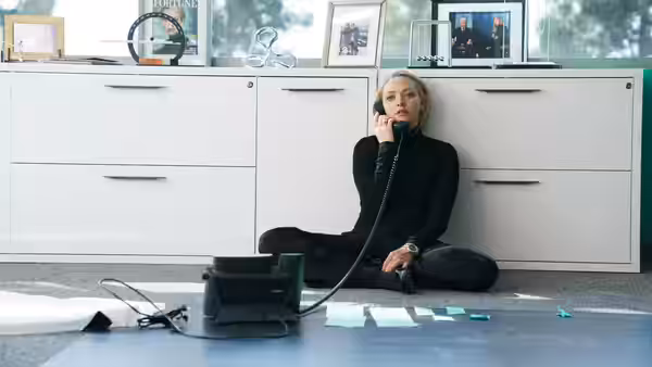 Elizabeth Holmes (Amanda Seyfried) sitting on the floor talking on the phone