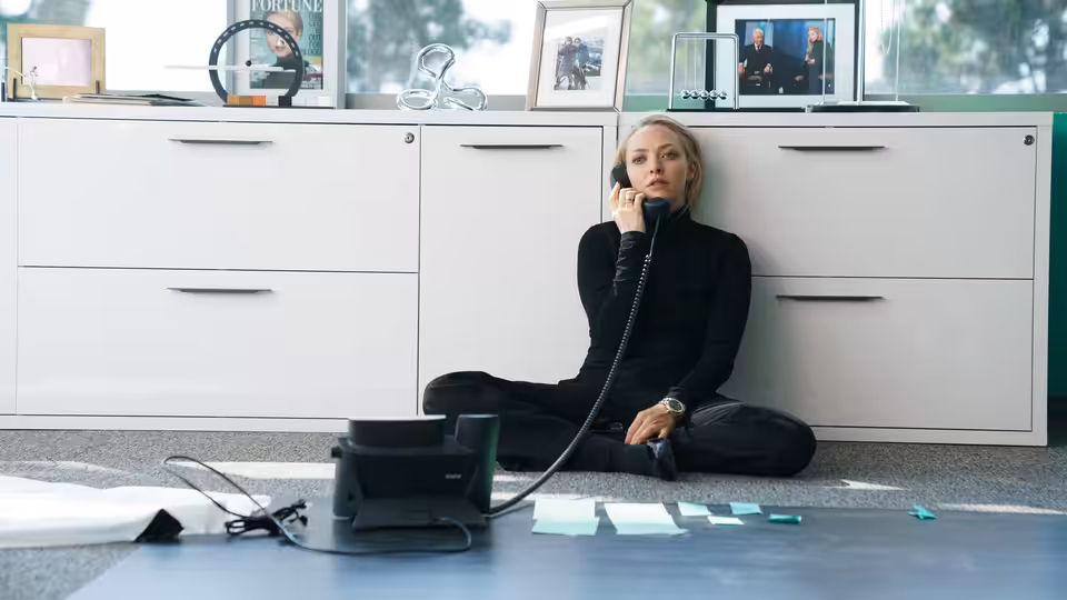 Elizabeth Holmes (Amanda Seyfried) sitting on the floor talking on the phone