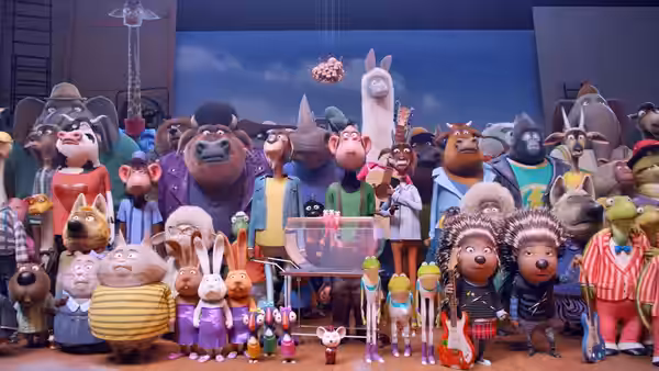 A large group of anthropomorphic animals gathered on stage around a transparent box