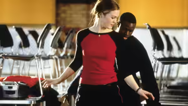 Sara Johnson (Julia Stiles) and Derek Reynolds (Sean Patrick Thomas) stand close in an auditorium