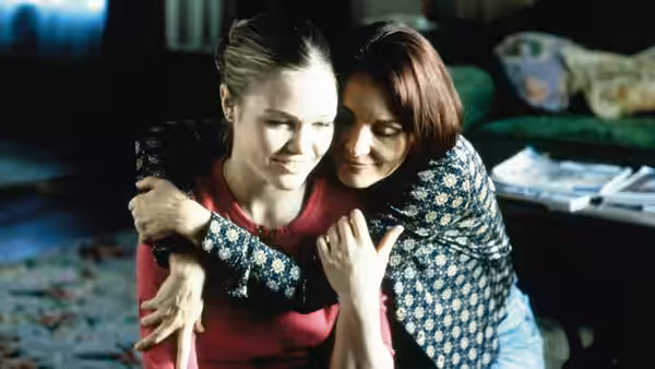 Sara Johnson (Julia Stiles) embraces another woman indoors on a couch