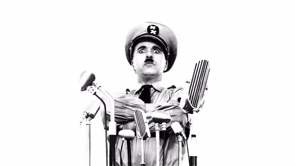Adenoid Hynkel (Charlie Chaplin) standing with arms crossed among microphones